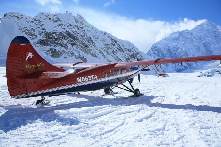 Red ski plane on snowy mountain landscape under clear sky.