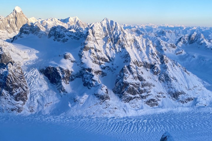 Aerial view of snow-covered mountain range at sunrise.